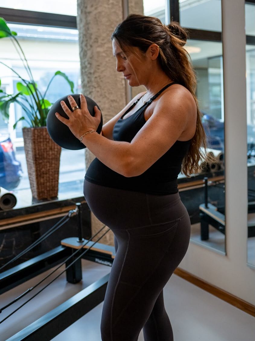 Werdende Mama trainiert mit Ball am Reformer