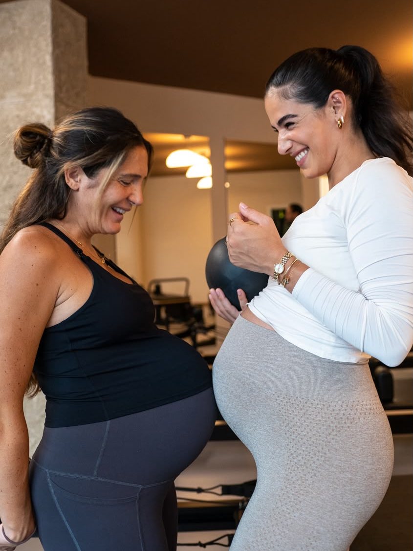 Zwei werdende Mamas lachen gemeinsam im Studio