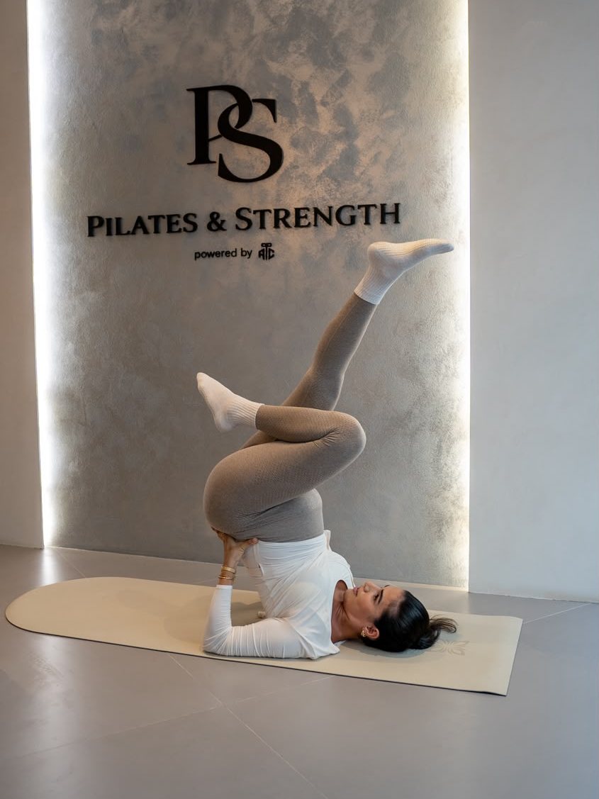Pilates-Übung vor der Logowand von Pilates & Strength